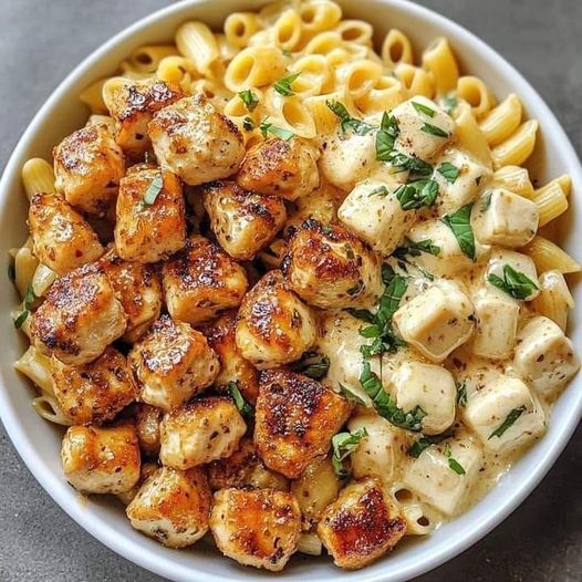 Delicious garlic butter chicken bites served over creamy Parmesan pasta, garnished with fresh parsley.